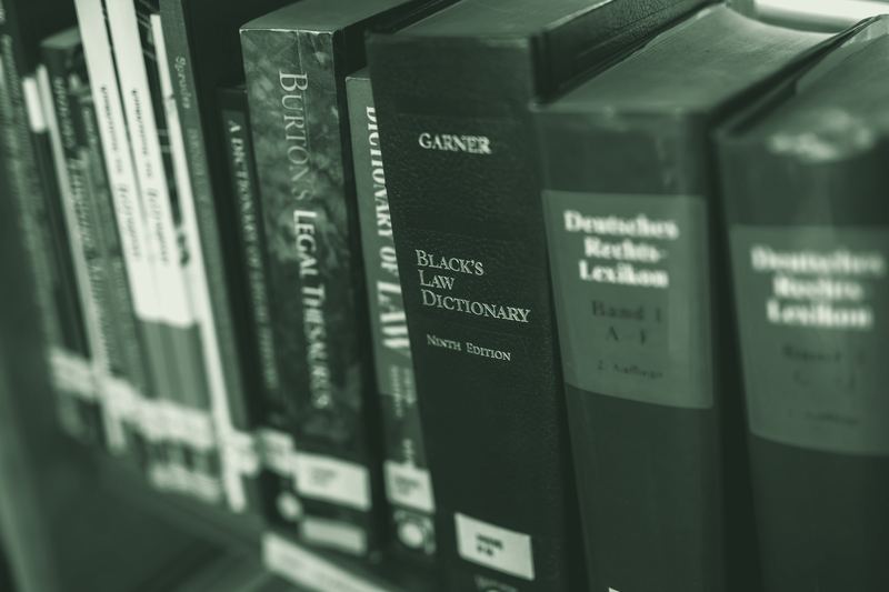 Law reference books on a shelf, including Black's Law Dictionary and a German legal lexicon